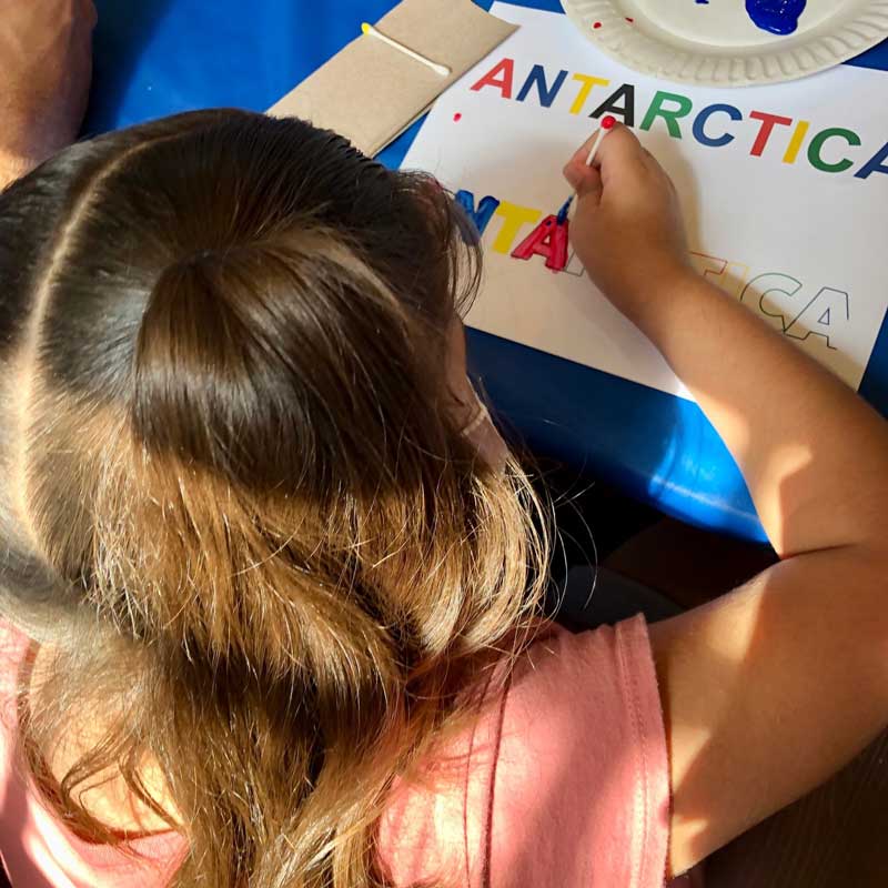 Girl with special needs colors the word Antarctica