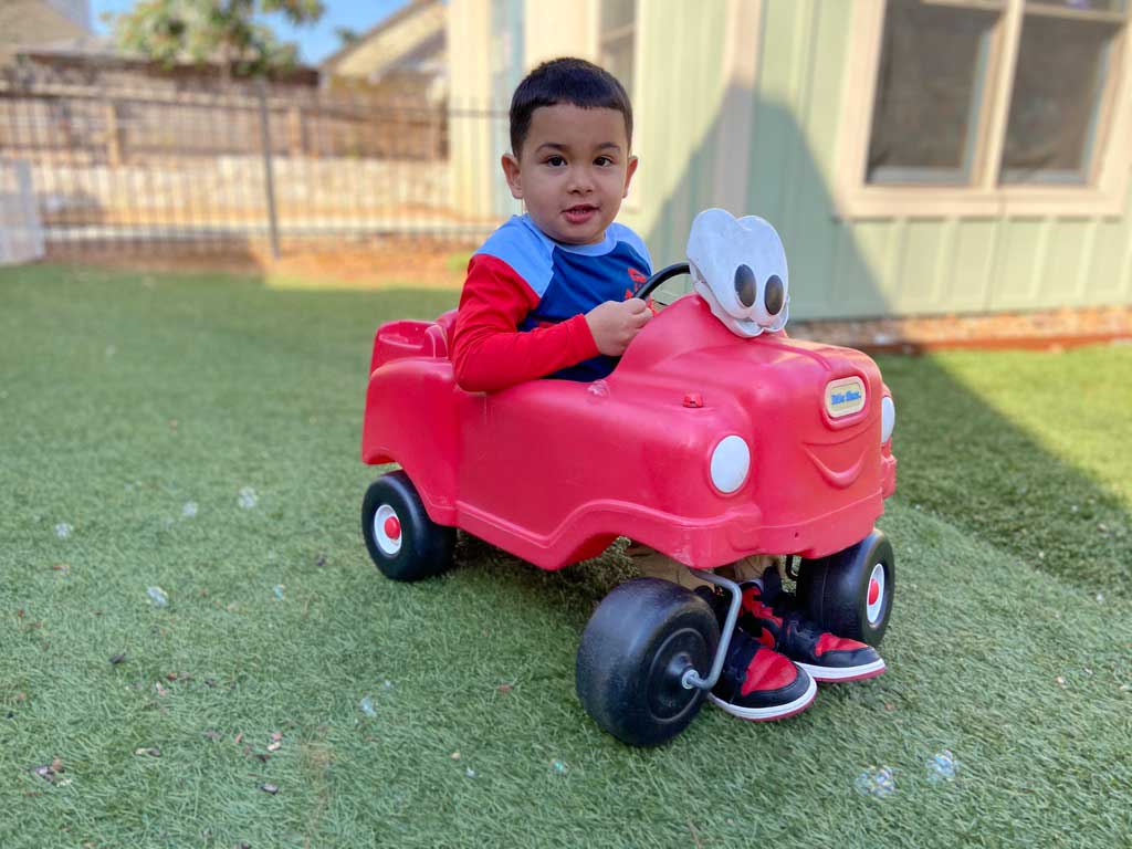 Un niño con necesidades especiales viaja en un pequeño coche rojo