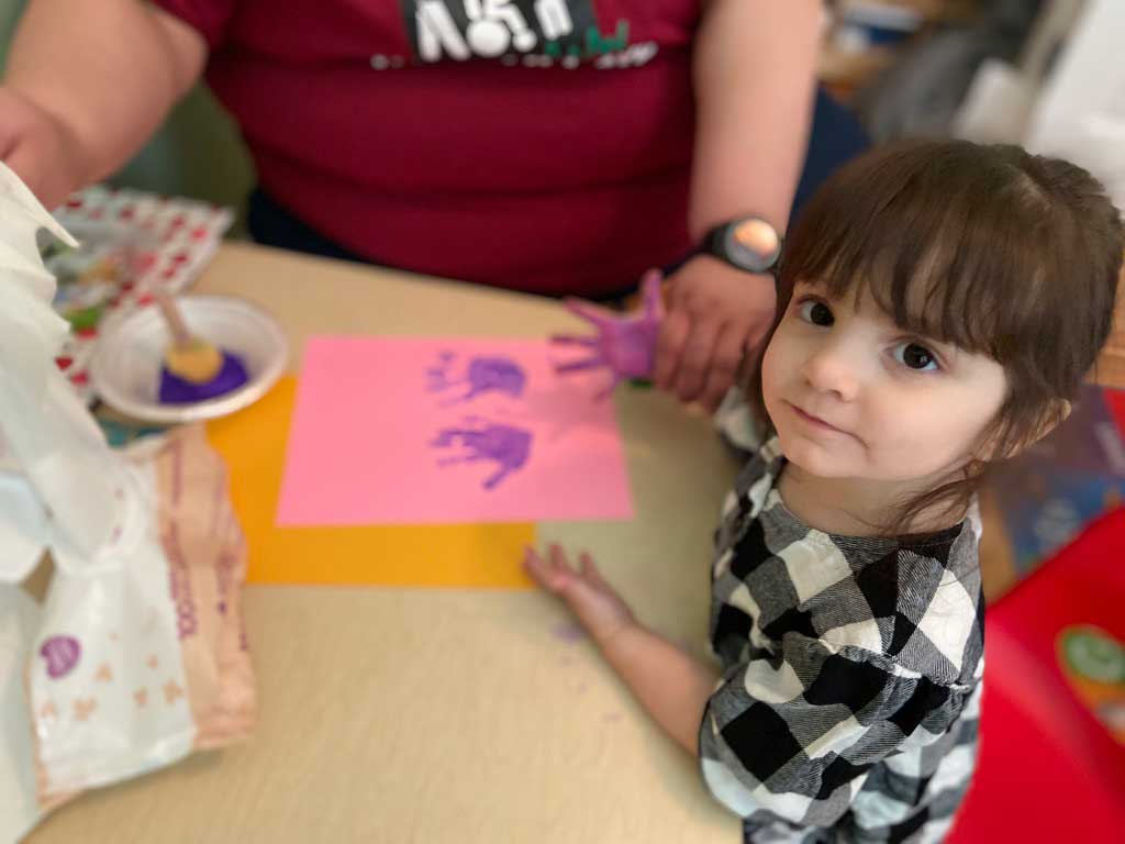 Little girl with special needs fingerprints with caregiver