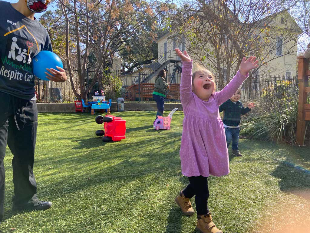 Little girl with down syndrome reaches into the air