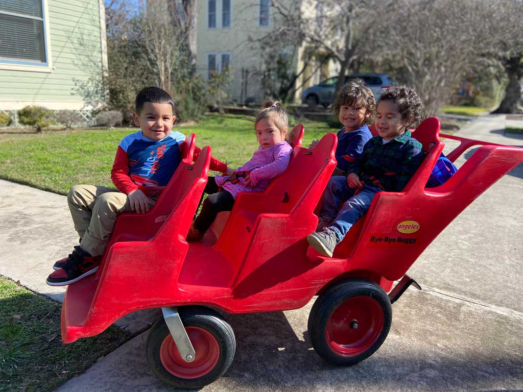 Cuatro niños sentados juntos en un cochecito rojo
