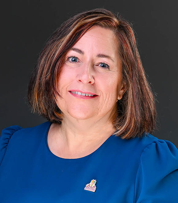A professional headshot of Rebecca Helterbrand, wearing a blue blouse and smiling at the camera