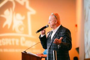 A male auctioneer with a microphone, RCSA logo behind him