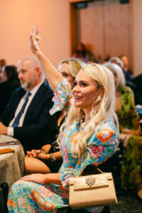 A woman in a formal blue flower dress participates in an auction