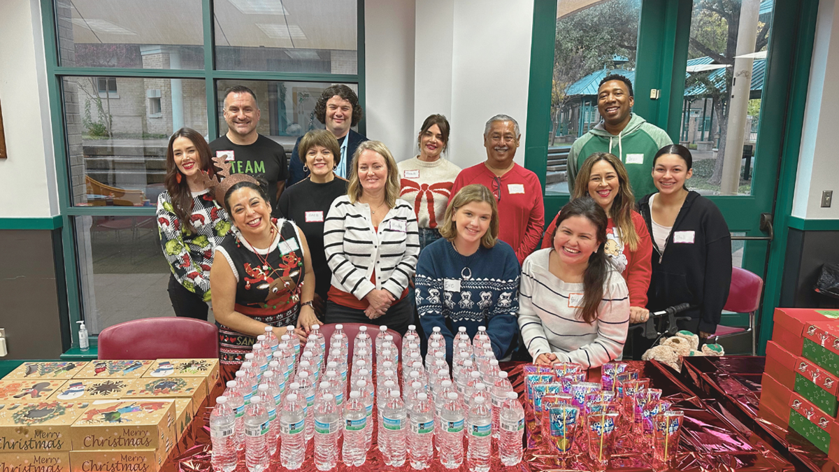 A group of volunteers sat smiling behind a table with water and snacks
