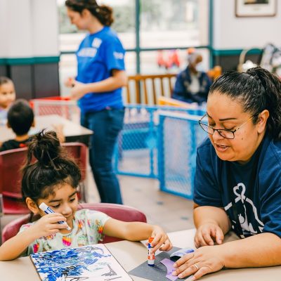Caregiver helping a young girl with an art project during RCSA’s Developmental Childcare Program